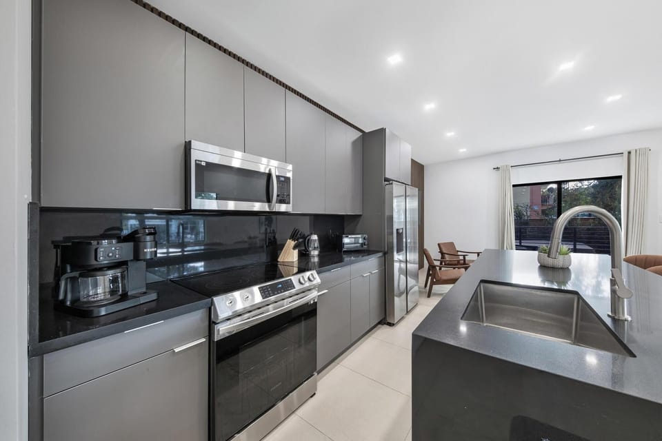 Sleek black kitchen w/ modern appliances & bold, dramatic finishes.

