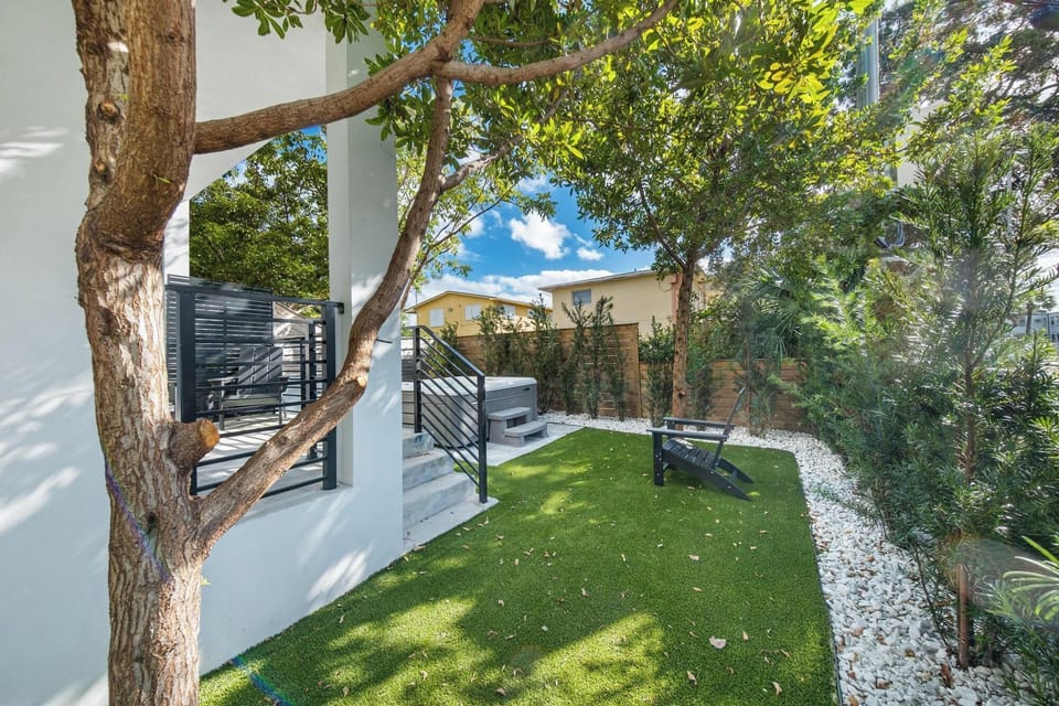 Shaded outdoor seating area with lush greenery and a hot tub for relaxation.