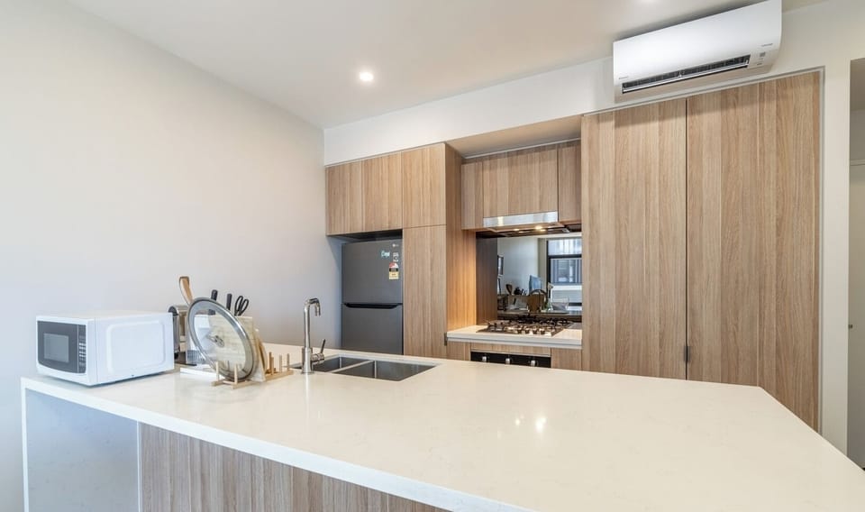 A neat and functional kitchen featuring light wood-toned cabinetry and a clean countertop.