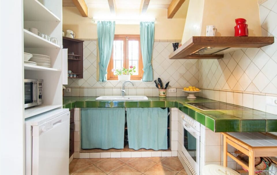 Fully equipped rustic kitchen at Villa Sa Mata, featuring tiled countertops, natural light and traditional Mallorcan style, perfect for preparing meals in a warm atmosphere.