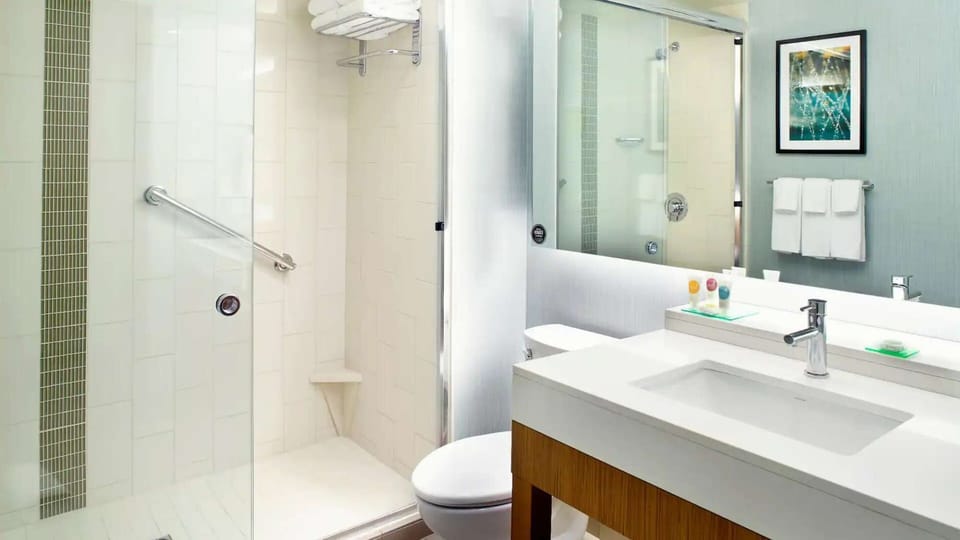 Shower bathroom with vanity, towels, and toiletries.