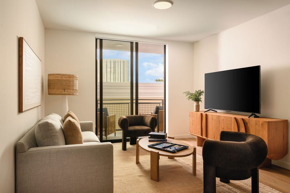The living area, with warm wood tones and floor-to-ceiling glass, creates an inviting space.