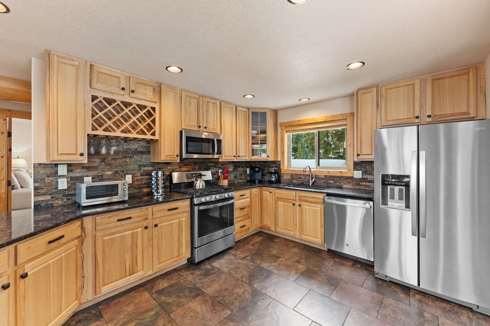 Your fully equipped kitchen awaits with warm wood cabinets, granite counters, and stainless steel appliances for memorable meals.