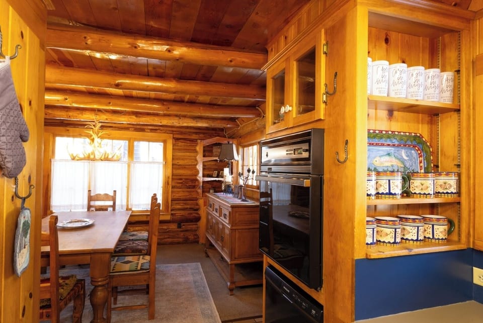 Step into your cozy cabin kitchen, where warm wood surrounds you, natural light streams through windows, and colorful accents welcome you to cook and gather together in rustic charm.