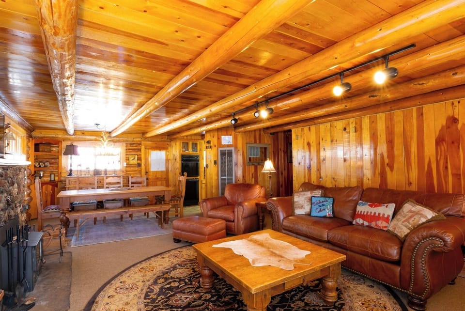 Unwind in your rustic living space with hand-hewn log beams overhead, plush leather seating, and a stone fireplace inviting you to relax after a day of adventure.