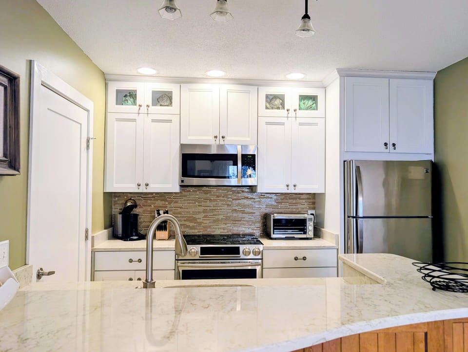 15002 Tall Pines Ct - Coastal Kitchen Overview - This wide perspective of the kitchen highlights the spacious granite-style countertops and the generous amount of storage. It’s a beautifully updated and fully equipped kitchen ready for anything from a casual breakfast to a family feast.