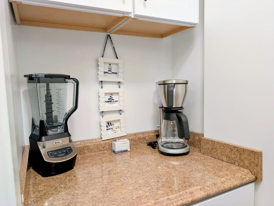 15002 Tall Pines Ct - Bar Nook & Pantry - A dedicated bar nook with beautiful granite-style countertops and open shelving offers a perfect spot for your coffee station or drink prep. The adjacent pantry door ensures you have ample storage for all your vacation supplies.
