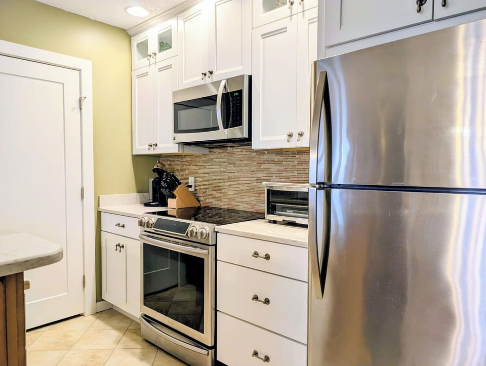15002 Tall Pines Ct - Modern Kitchen Suite - This efficient kitchen features modern stainless steel appliances, including a large refrigerator and a built-in microwave over the stove. The crisp white cabinetry and neutral backsplash ensure a bright and clean culinary space.