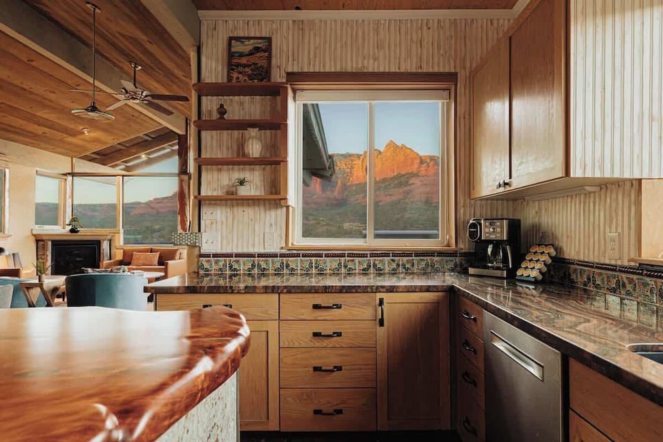 Wake up to stunning red rock vistas while brewing your morning coffee in this warm, wood-accented kitchen with granite counters and colorful tile backsplash.
