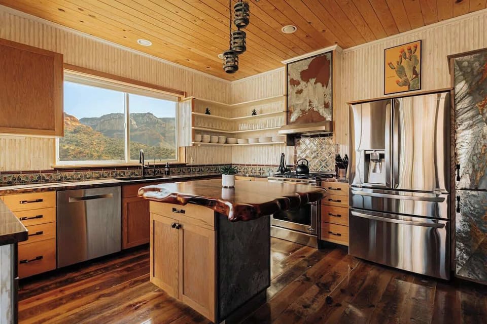 Your gourmet kitchen features rustic wood finishes, premium stainless appliances, and stunning mountain views perfect for cooking memorable meals.