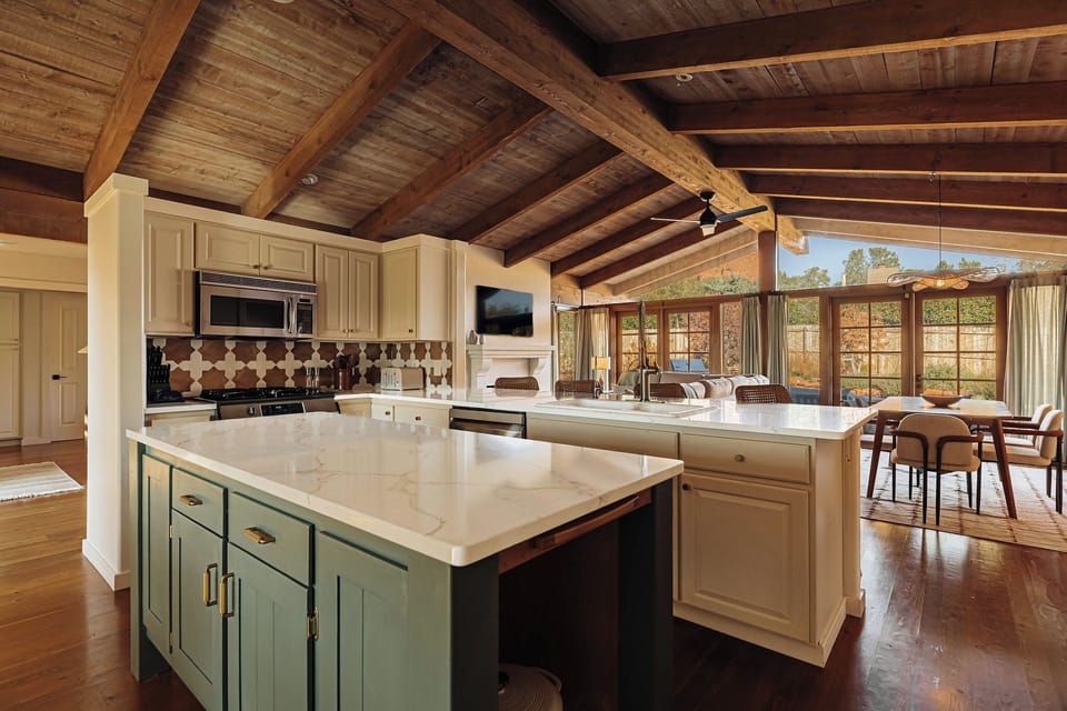 Your spacious gourmet kitchen invites culinary adventures beneath soaring rustic beams, with marble countertops and charming dining nook overlooking scenic views.