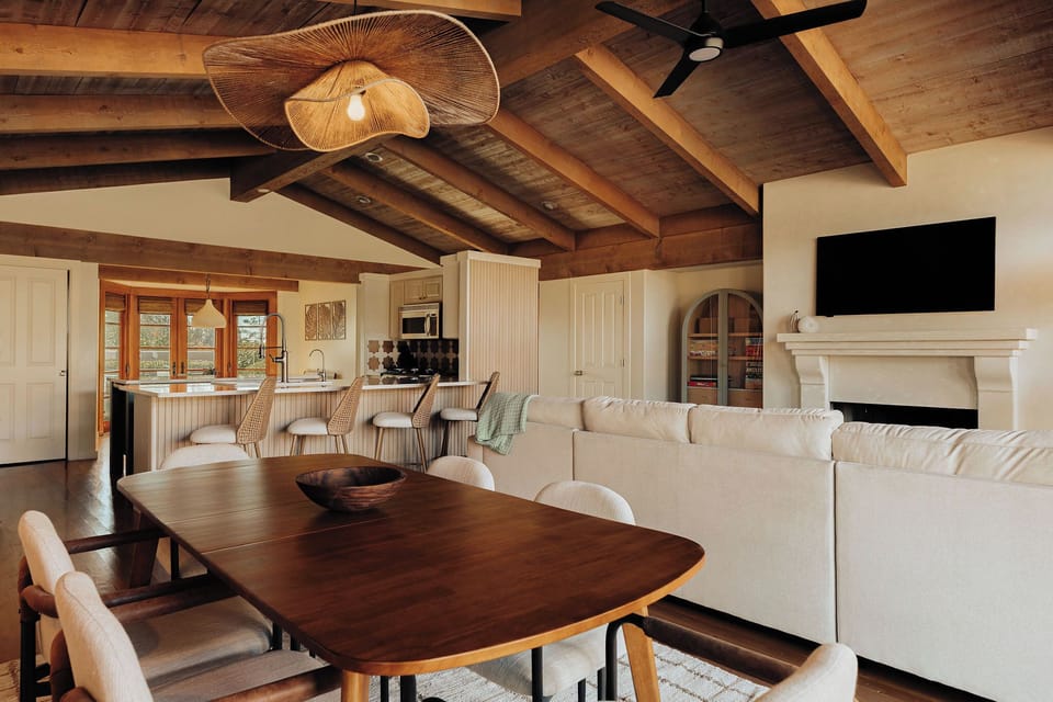 Unwind in your open-concept living space where rustic ceiling beams meet modern comfort, complete with a cozy fireplace for evening relaxation.