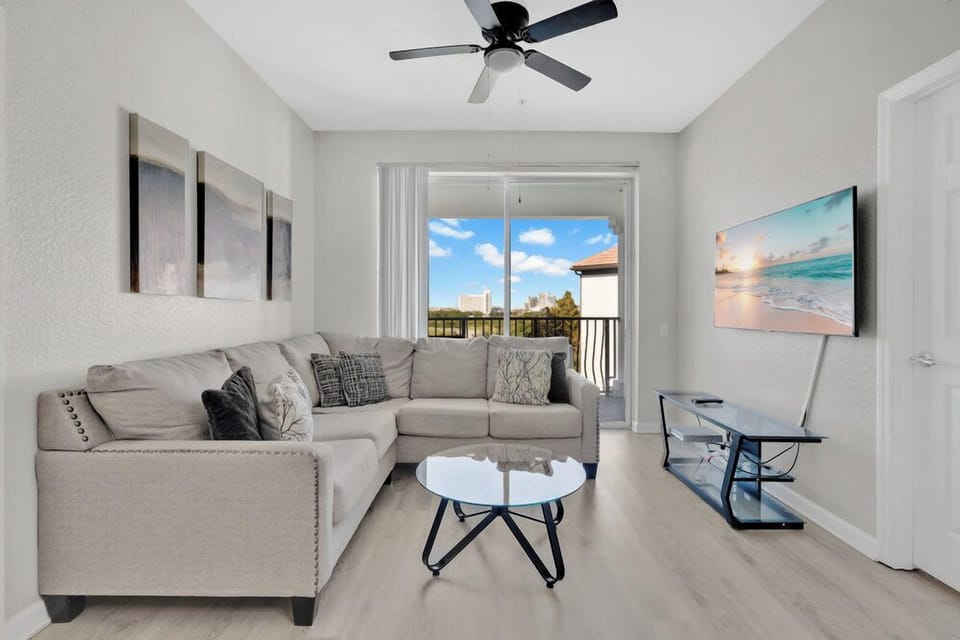 Relax in your bright living space with plush sectional seating, modern decor, and balcony views of the city skyline.
