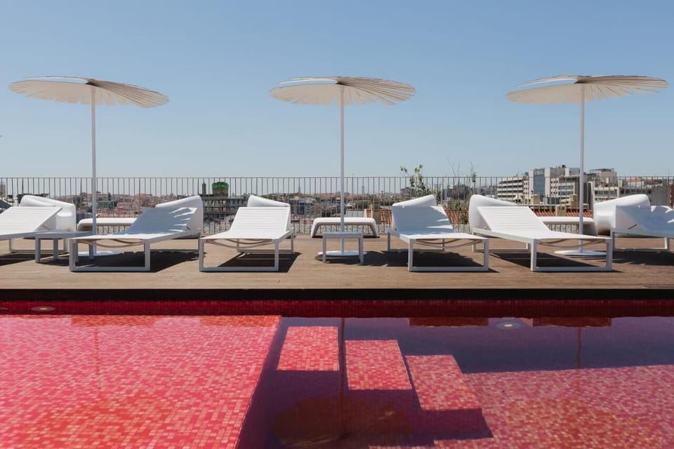 Unwind poolside on sleek loungers under sunny city skies.