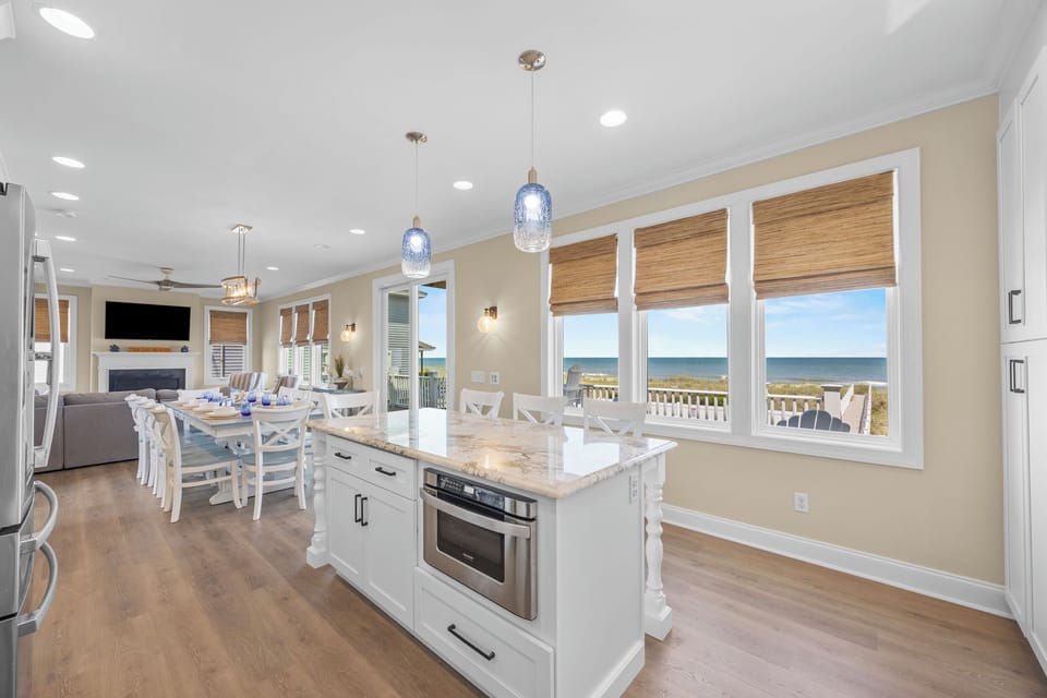 Picture yourself cooking and dining with unobstructed ocean views streaming through every window—this bright, coastal kitchen flows seamlessly into the living area, perfect for gathering and relaxing.