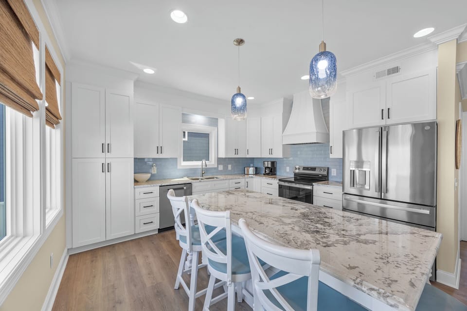 Your fully-equipped coastal-chic kitchen invites effortless meal prep with gleaming granite counters, stainless appliances, and serene blue-tiled backsplash—perfect for gathering around the spacious island.
