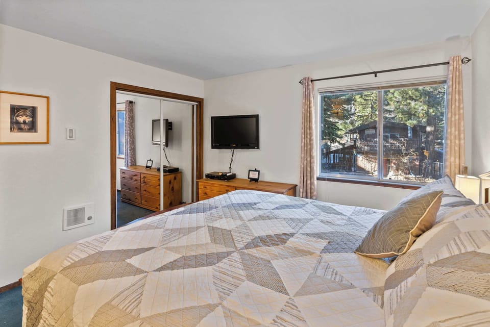 The lower-level primary bedroom features a comfortable king-size bed, a private TV.