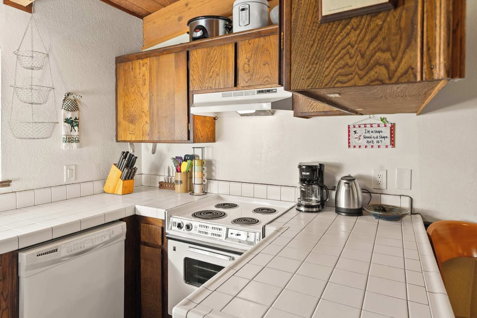 Fully equipped kitchen with tiled counters, white appliances, and a morning coffee station.
