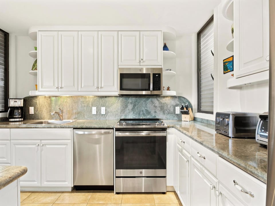 Step into your fully equipped kitchen where cooking feels effortless. Crisp white cabinetry, stainless steel appliances, and elegant stone countertops create a bright, welcoming space for preparing vacation meals together.
