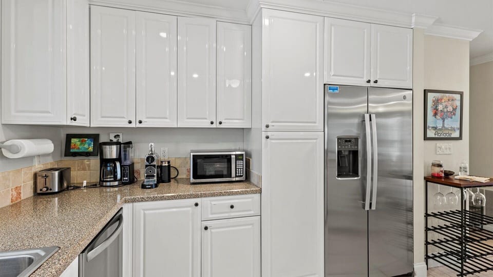 The kitchen shares the open floor plan with the living and dining areas and has a fridge, oven, stove, microwave, dishwasher, coffee maker, toaster, and expresso machine.