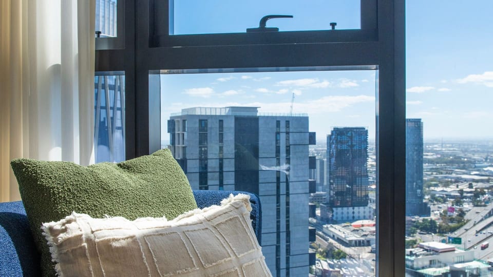 Bedroom corner with city skyline views and styled cushions