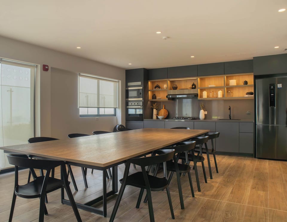 Large indoor dining area with a long wooden table and modern kitchen.