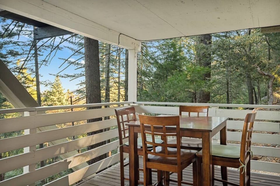 Covered deck with outdoor dining surrounded by peaceful forest views