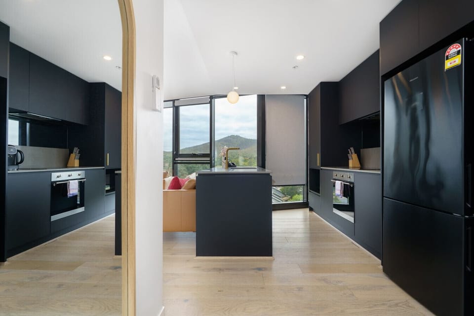 A sleek, modern kitchen fully equipped for easy home cooking, with quality appliances and plenty of bench space.