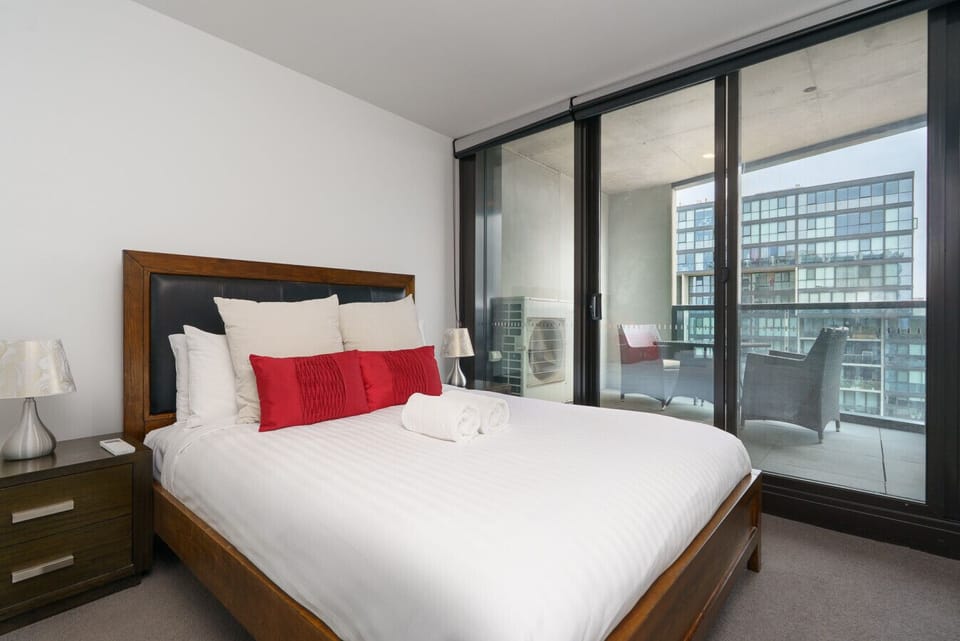 Relax in a quiet bedroom with large windows and a soothing outlook. A comfortable retreat at the end of the day.