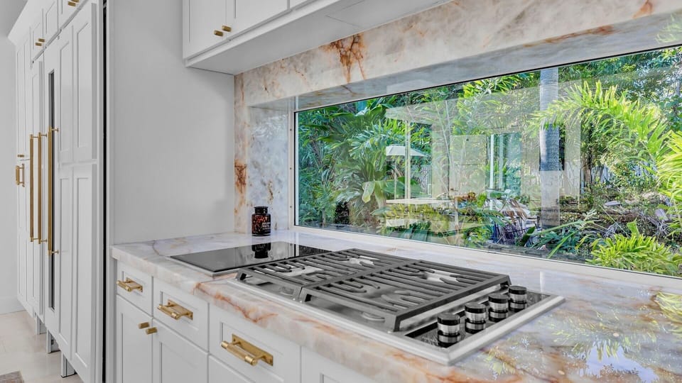Cook with inspiration in your gourmet kitchen, featuring marble counters and garden views through expansive windows.
