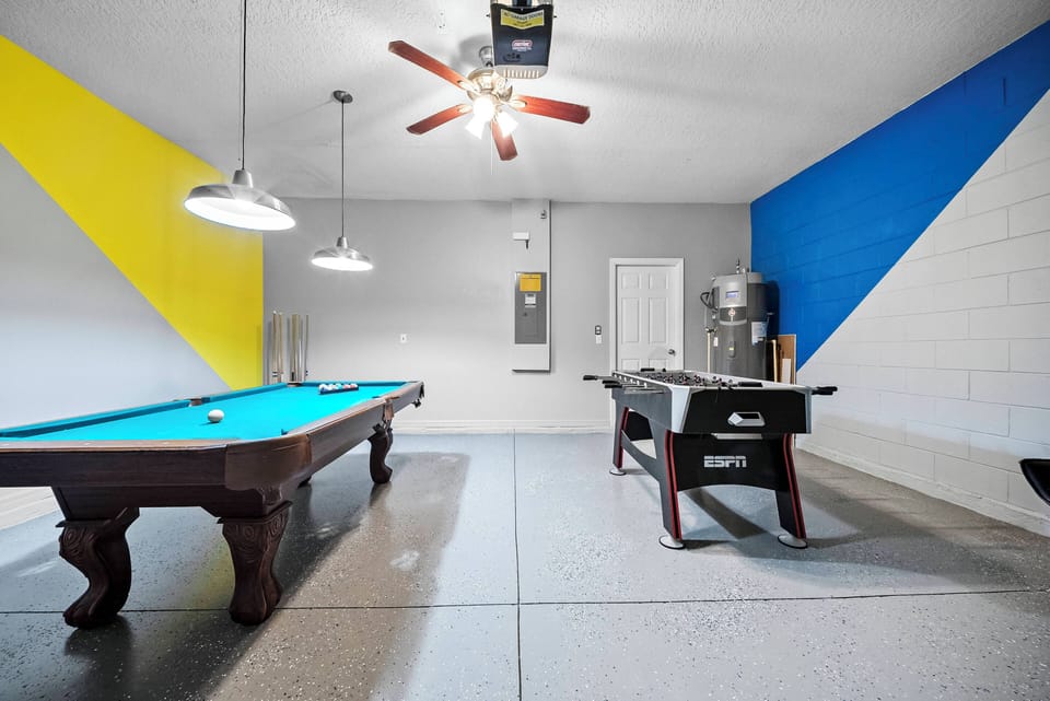Step into this vibrant game room where a sleek pool table awaits your next match beneath stylish pendant lighting. The bold blue and yellow accent walls add a playful touch, creating an energetic atmosphere for fun and relaxation.