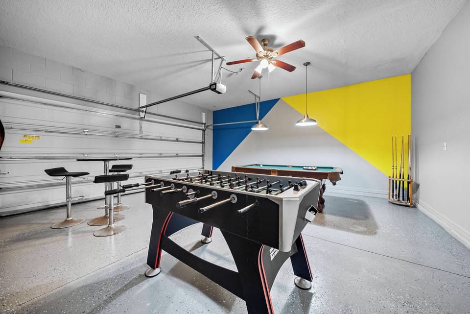 Welcome to our vibrant game room, where you can enjoy friendly competition at the foosball table or billiards setup. The lively yellow and blue accents enhance the atmosphere, while modern bar stools provide a comfy spot to relax.