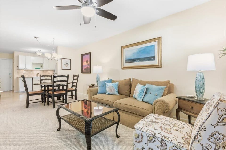 Open living area with coastal decor, a large smart TV, and access to the sunny Carolina room.