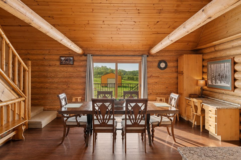 Rustic log cabin dining room with deck access and scenic country views
