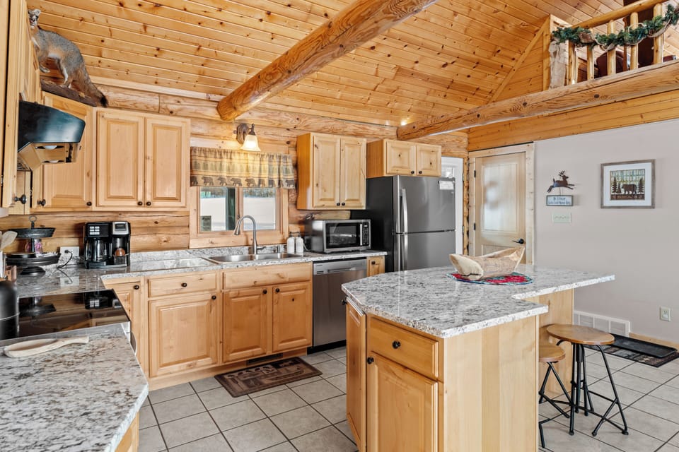 Spacious log kitchen with granite counters, stainless appliances, island seating