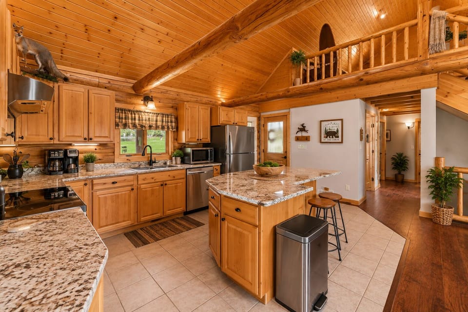 Cozy log cabin kitchen with granite island and warm wood interiors