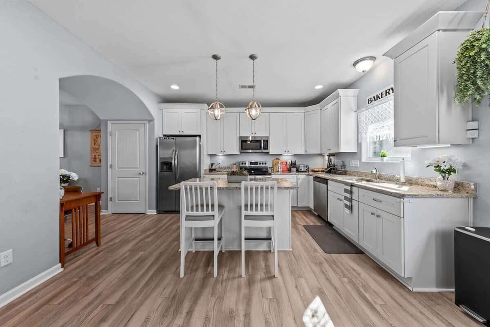 Open kitchen w/ island seating, bright cabinetry & modern finishes