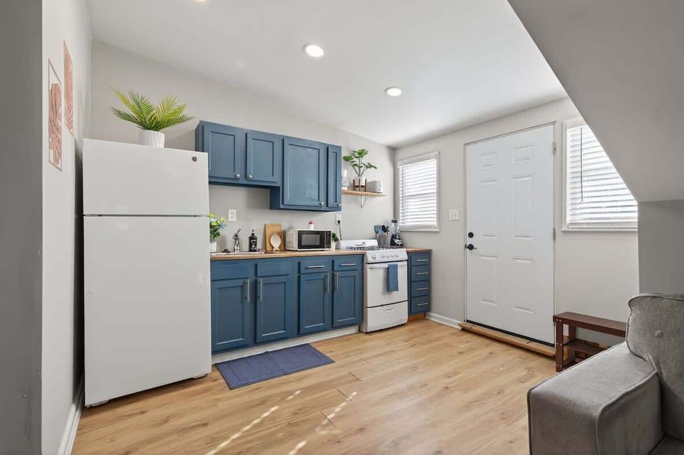 The kitchen and living area combine to create an efficient, open space. Blue cabinets add character while natural light brightens the entire room. 