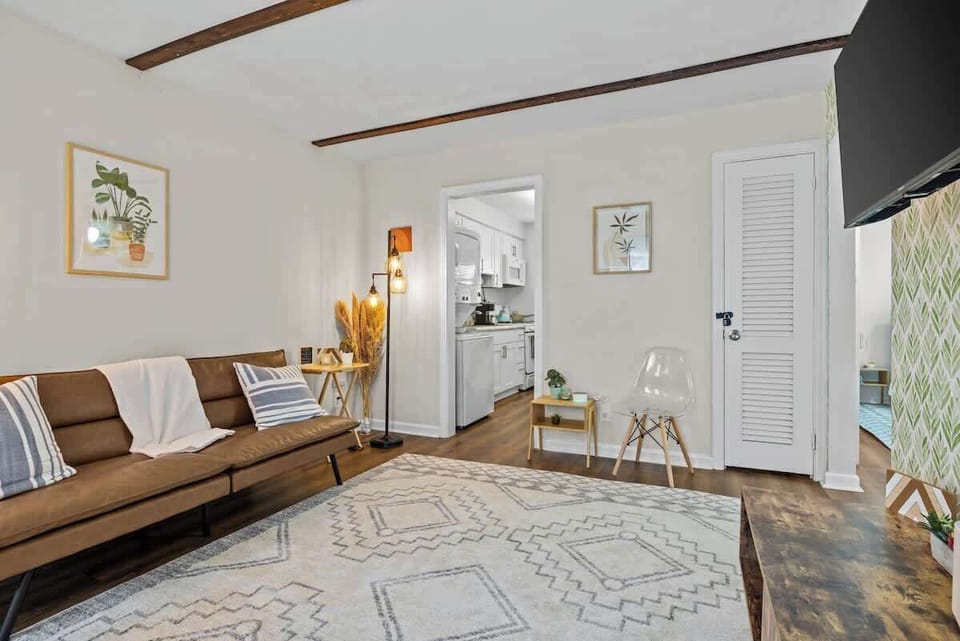 Wide living room view highlighting open flow, seating area & bright windows