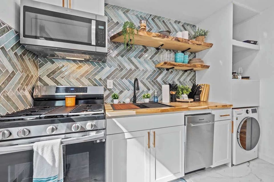 Modern kitchen w/ patterned backsplash, open shelving & sleek appliances