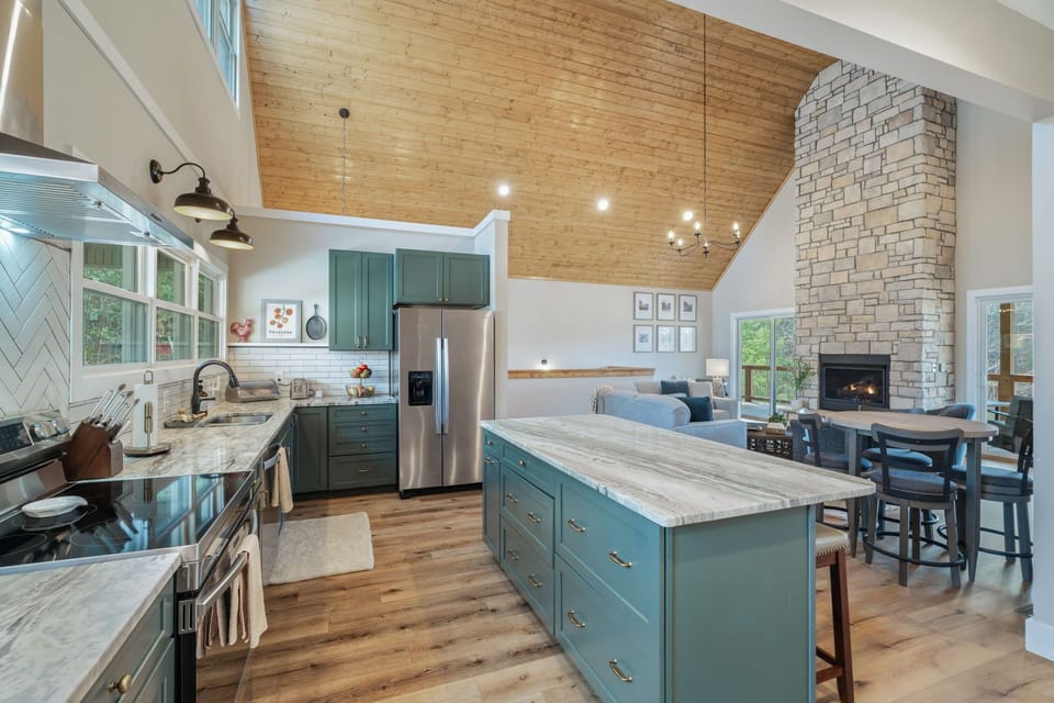 Your spacious open-concept kitchen features beautiful sage cabinetry, marble countertops, and a cozy stone fireplace for unforgettable culinary experiences.