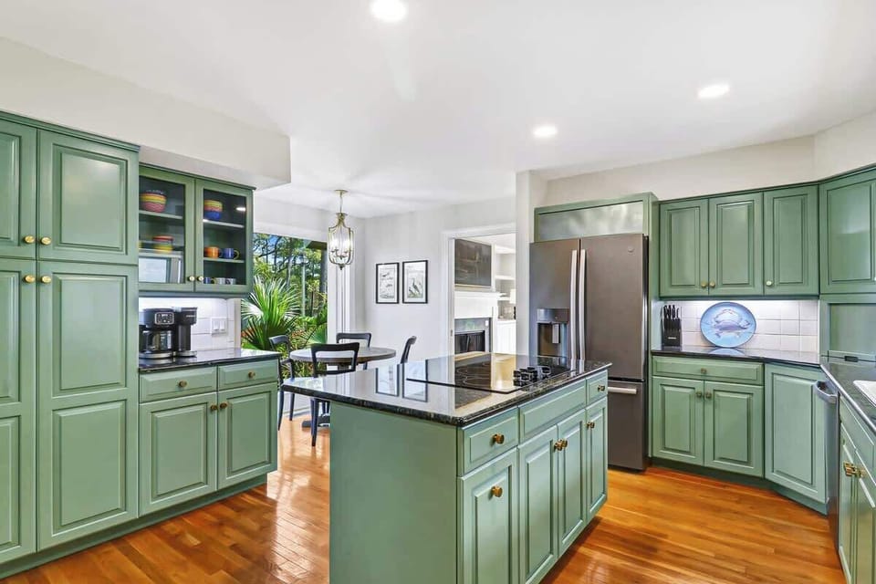 Cook and entertain with ease in your spacious kitchen featuring sage-green cabinetry, granite countertops, and premium appliances.