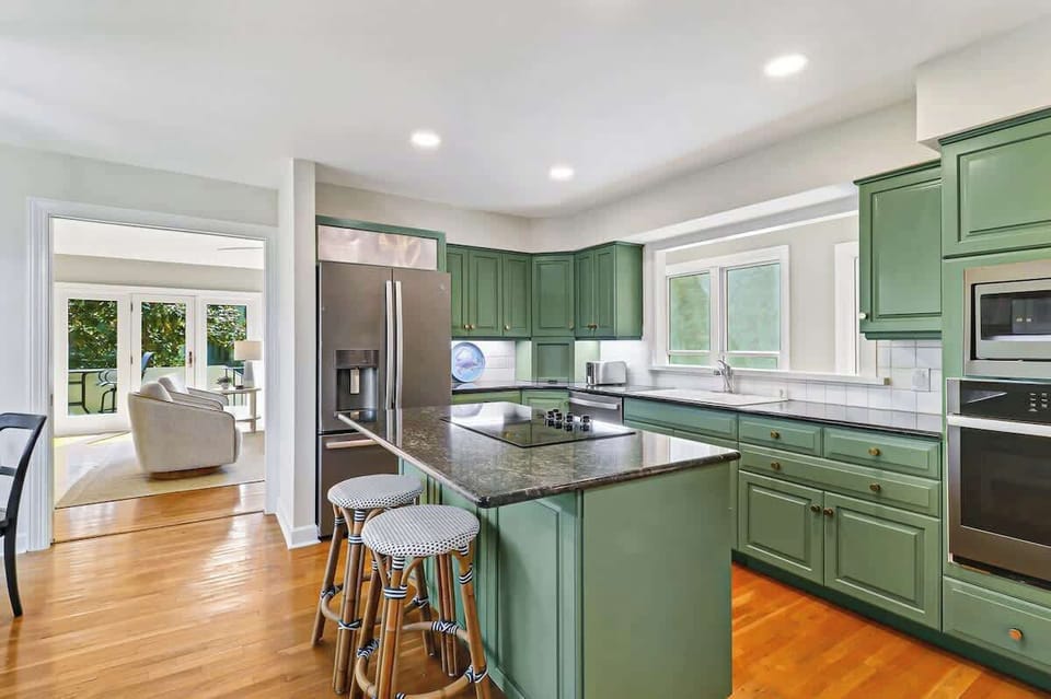 Your spacious kitchen features stunning sage-green cabinets, granite countertops, and modern stainless steel appliances - perfect for creating memorable meals together.