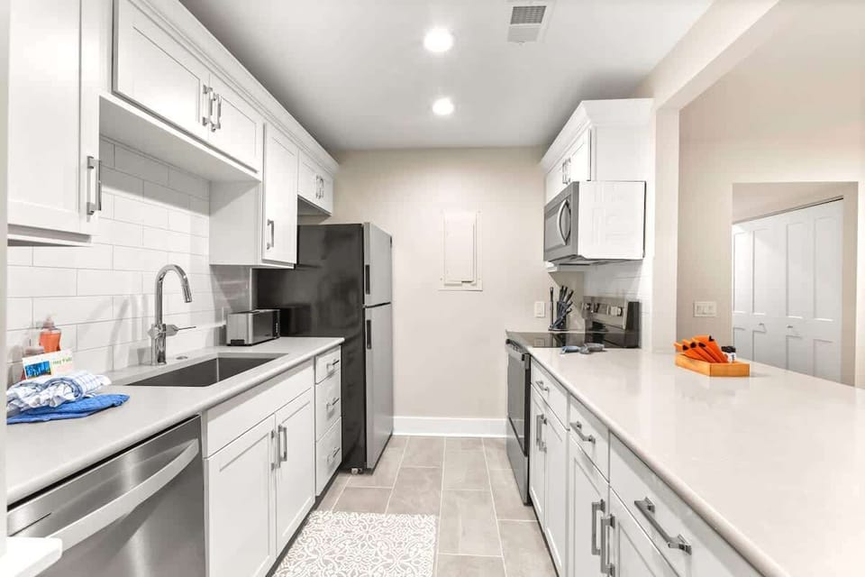 Your fully equipped modern kitchen features crisp white cabinetry, granite countertops, and stainless steel appliances for effortless meal preparation.