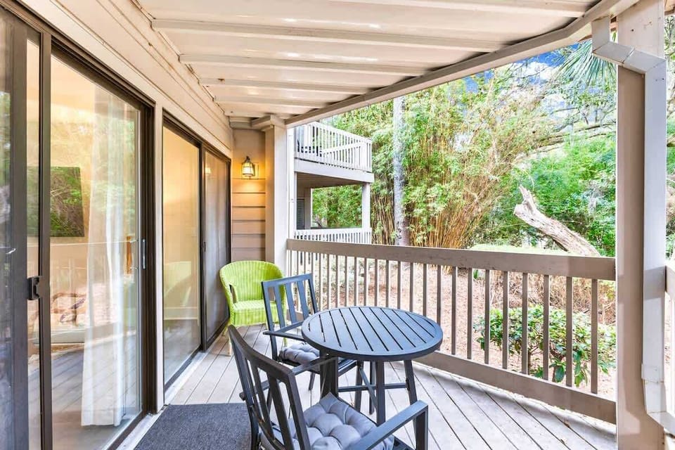 Covered patio with seating overlooking a wooded area