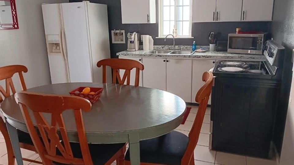 Kitchen and dining area with refrigerator, stove, and table