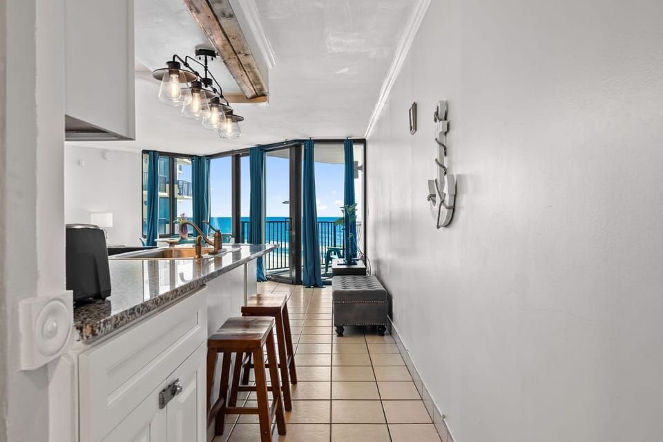 modern kitchen with bar seating and ocean views through floor-to-ceiling windows