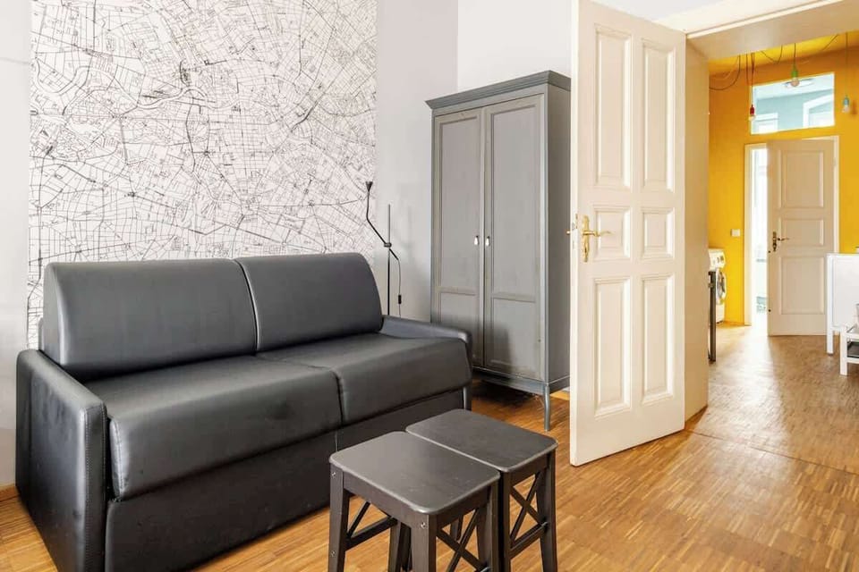 Wohnbereich mit elegantem Ledersofa vor einer 5 qm großen Berlin-Karte.