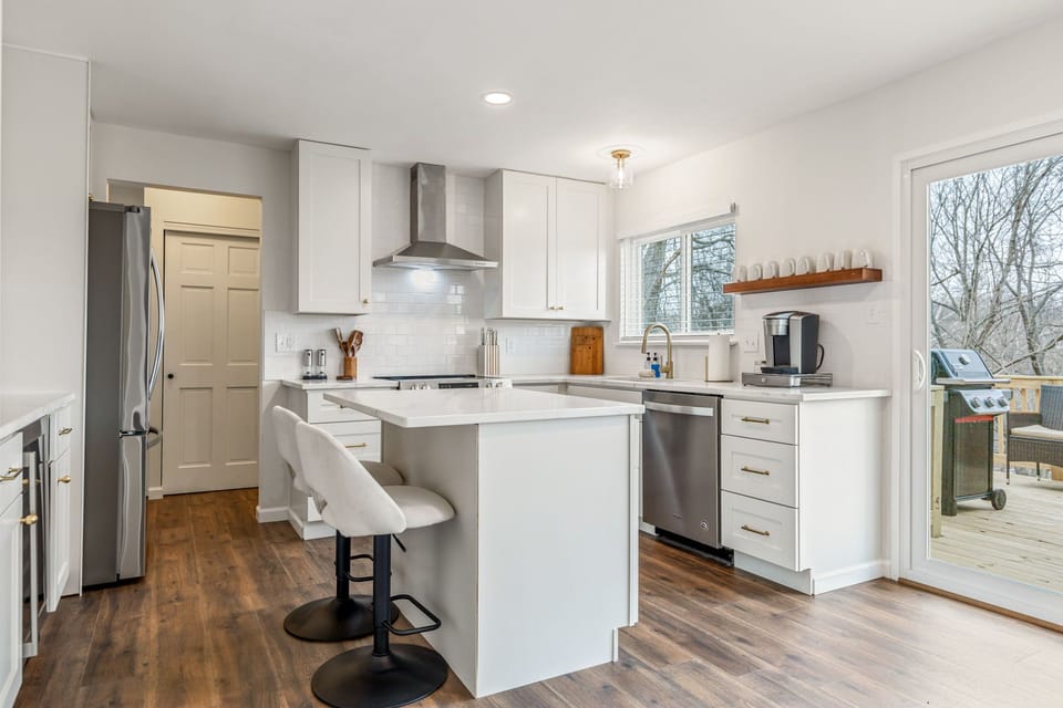 The kitchen breakfast bar adds casual seating beside the white cabinetry and open preparation area.