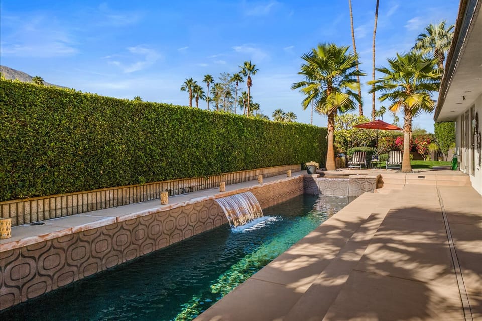 Resort-style pool with waterfall feature and mountain backdrop